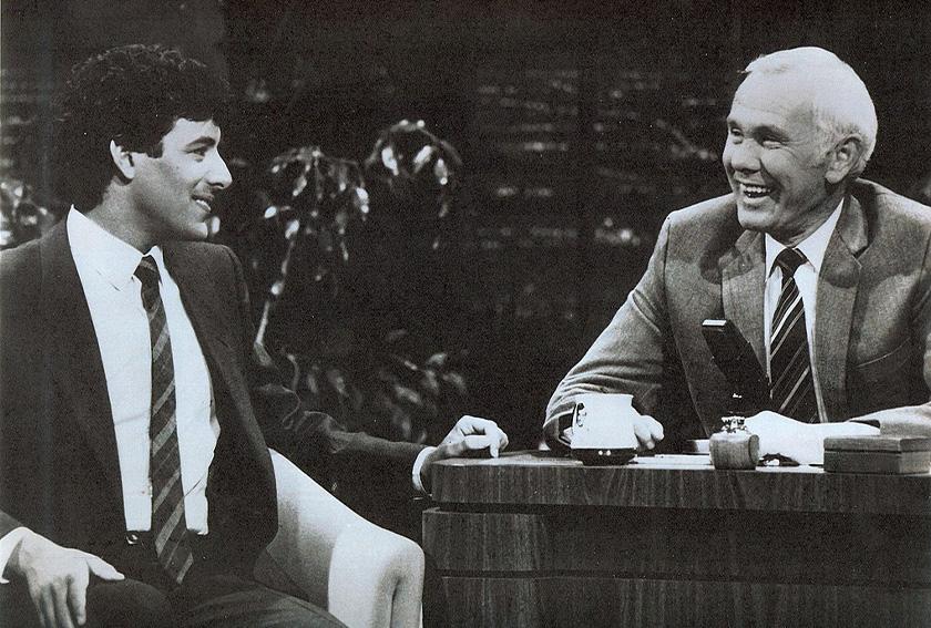 Johnny Carson Sits at His Desk Interviewing A Guest